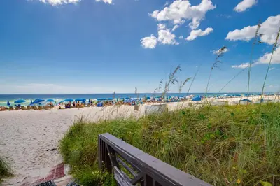 a sandy beach with people sitting under umbrellas at Shores of Panama 1408 - Seaside Getaway in Panama City Beach