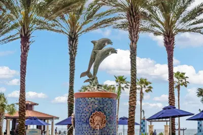 a statue of a bird sitting on top of a pot with palm trees at Shores Of Panama #1509 in Panama City Beach