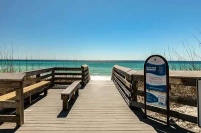 a boardwalk leading to the beach with a sign at Pelicans Nest II - Easy walk to the beach & Pool in Santa Rosa Beach