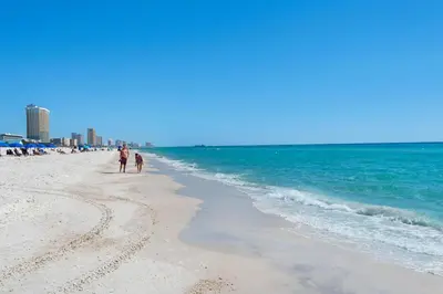a man and a child walking on the beach at Sunbird 601W in Panama City Beach