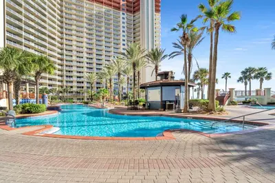 a swimming pool with palm trees and a large building at Shores of Panama 1002 in Panama City Beach