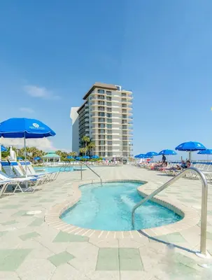 a swimming pool with chairs and umbrellas and a building at Edgewater Villa 3011 'Fountain View Hideaway' in Panama City Beach