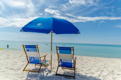 two chairs under an umbrella on a beach at Edgewater 3-0905 'Gone Coastal' in Panama City Beach