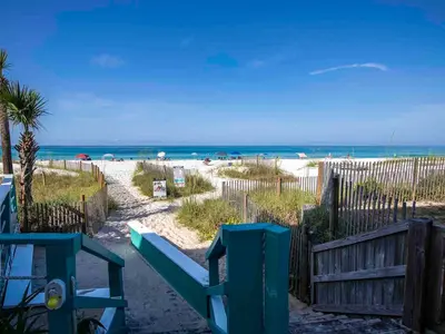 a beach with a blue bench and the ocean at Horizon South #57-203 in Panama City Beach