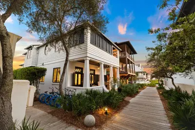 a white house with a wooden walkway at Abba Cottage in Rosemary Beach