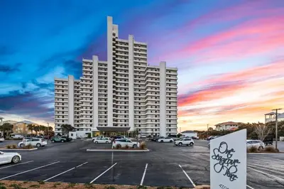 a large white building with cars parked in a parking lot at One Seagrove Place 0608 in Santa Rosa Beach