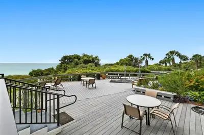 a deck with tables and chairs and the ocean at One Seagrove Place 1507 in Santa Rosa Beach