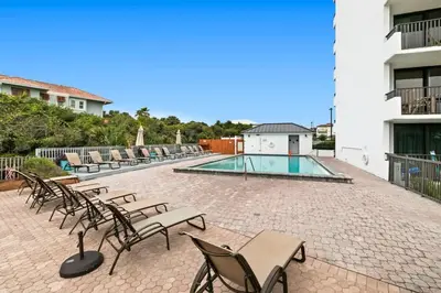 a group of chairs and a swimming pool on a patio at One Seagrove Place 1201 in Santa Rosa Beach