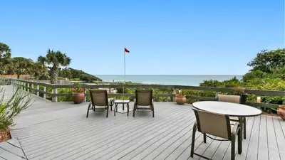 a wooden deck with chairs and tables and the ocean at One Seagrove Place 0207 in Santa Rosa Beach