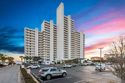 a large white building with cars parked in a parking lot at One Seagrove Place 0305 in Santa Rosa Beach