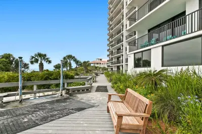 a wooden bench sitting on a walkway next to a building at One Seagrove Place 1606 in Santa Rosa Beach