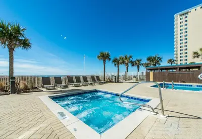 a swimming pool with palm trees and a building at Ocean Villa 2004 by Emerald Coast Retreats Unit in Panama City Beach