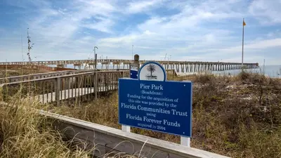 a sign on a beach with a pier in the background at Villas Bahama West 106 in Panama City Beach
