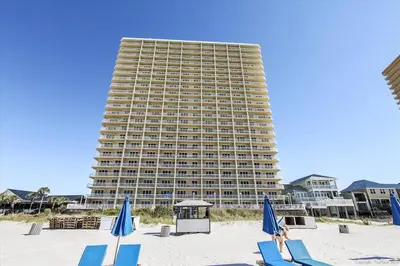 a large building on the beach with chairs and umbrellas at 909-Seychelles in Panama City Beach