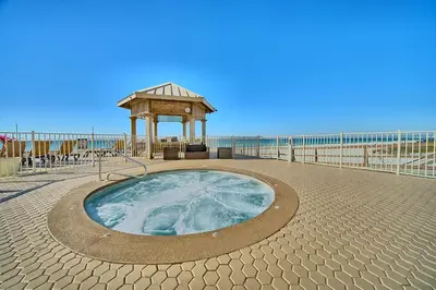 a hot tub with a gazebo next to the beach at Treasure Island 1612 in Panama City Beach
