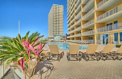 a row of chairs next to a swimming pool at a resort at Treasure Island 1806 in Panama City Beach