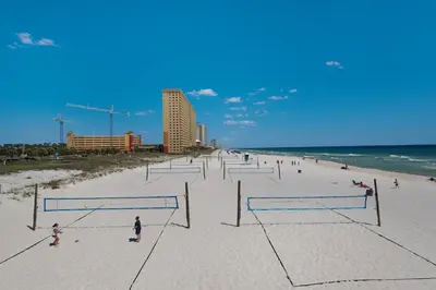 a group of people playing volleyball on a beach at Charming 3/2 Beach House w/ POOL & Golf Cart INCLUDED - 1 Min Walk to Beach in Panama City Beach