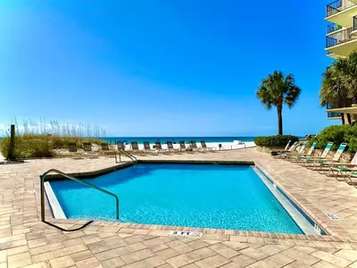 a swimming pool with chairs and the beach at Pelican Walk 504 in Panama City Beach