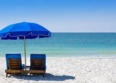 two chairs under an umbrella on a beach at Pelican Walk 106 in Panama City Beach