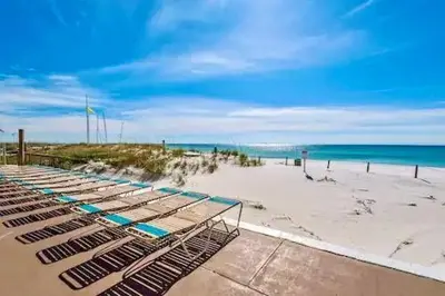 a beach with several lounge chairs on the sand at Pelican Walk 106 in Panama City Beach