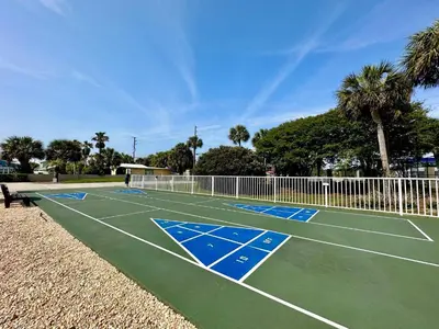 a tennis court with palm trees in the background at Pelican Walk 211 in Panama City Beach