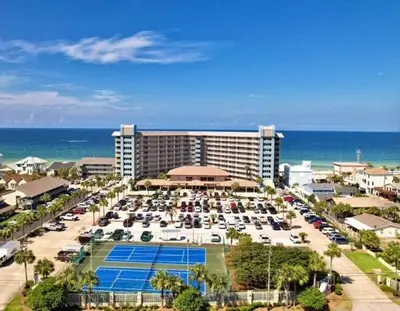 a hotel with cars parked in a parking lot next to the ocean at Pelican Walk 402 in Panama City Beach
