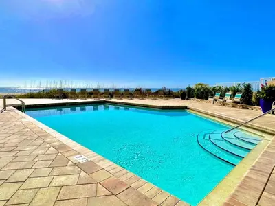 a swimming pool with blue water and chairs at Pelican Walk 611 in Panama City Beach