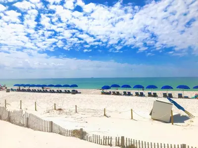 a beach with umbrellas and chairs and the ocean at Pelican Walk 609 in Panama City Beach