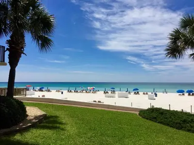 a beach with chairs and umbrellas and the ocean at Pelican Walk 108 in Panama City Beach