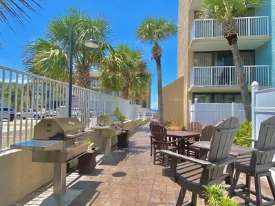 a patio with tables and chairs and palm trees at Pelican Walk 410 in Panama City Beach