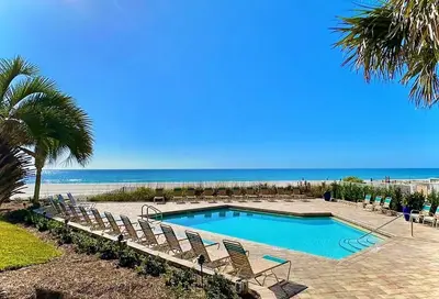 a swimming pool with chairs and the beach at Pelican Walk 502 in Panama City Beach