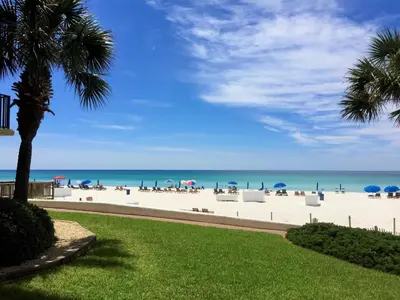 a beach with chairs and umbrellas and the ocean at Pelican Walk 1009 in Panama City Beach