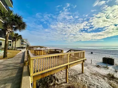 a wooden walkway to the beach with a palm tree at Pelican Walk 710 in Panama City Beach