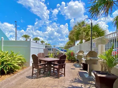a patio with a table and chairs and a fence at Pelican Walk 706 in Panama City Beach