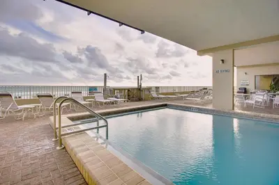 a swimming pool with tables and chairs and the ocean at Gulfgate 201 in Panama City Beach