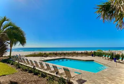 a swimming pool with chairs and the beach at Pelican Walk 107 in Panama City Beach