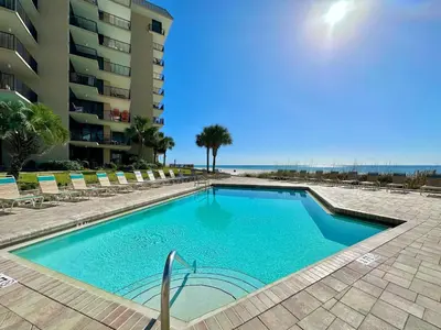 a swimming pool with chairs next to a building at Pelican Walk 107 in Panama City Beach