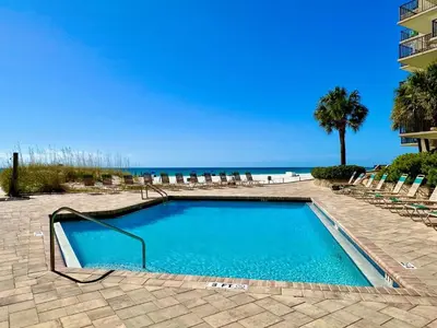 a swimming pool with chairs and the beach at Pelican Walk 207 in Panama City Beach