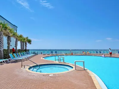a large swimming pool with the ocean in the background at Tidewater 1916 in Panama City Beach