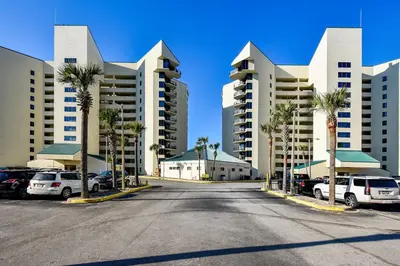 a parking lot with palm trees and tall buildings at Sunbird Beach Resort 1011W By Book That Condo in Panama City Beach