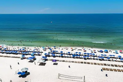 a beach with many umbrellas and people in the ocean at Calypso 2-103 West in Panama City Beach
