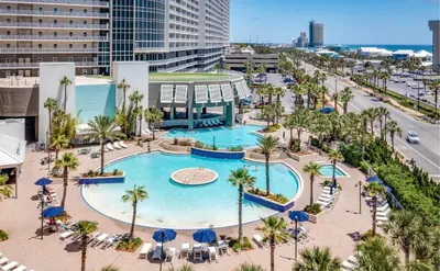 an aerial view of a pool with palm trees and buildings at Family and Friends Beach Resort Condo for 8! Steps from the Beach! By Dolce Vita Getaways! in Panama City Beach