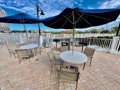 two tables and chairs with umbrellas on a patio at Family and Friends Beach Resort Condo for 8! Steps from the Beach! By Dolce Vita Getaways! in Panama City Beach
