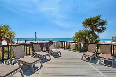 a wooden deck with chairs and the beach at Sunbird Resort! Stunning Remodeled Beachfront Condo! Free Beach Chair Service! by Dolce Vita PCB! in Panama City Beach