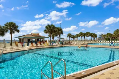 a large swimming pool with palm trees and a beach at The Summit 828 in Panama City Beach