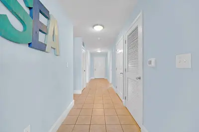 a hallway with white walls and a tile floor at The Blue Turtle Laketown in Panama City Beach