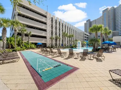 a pool with chairs and a table and a volleyball court at Emerald Beach #1032 in Panama City Beach