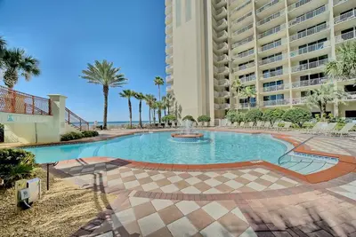 a swimming pool in a resort with palm trees and a building at Pineapple Paradise, Beach Front, Newly Renovated, Sleeps 6 in Panama City Beach