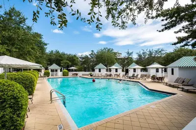 a swimming pool at a resort with chairs and trees at Highland Carriage House in Rosemary Beach