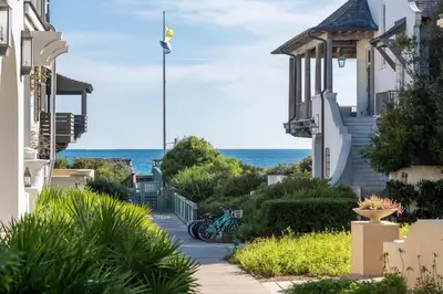 a walkway between houses with the ocean in the background at Lola's Carriage House in Rosemary Beach